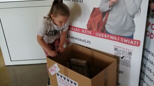 Akcja charytatywna dziewczynka wrzuca dary do pudełka