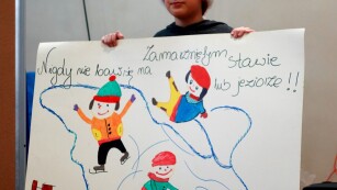 Uczeń pokazuje plakat o bezpiecznych feriach