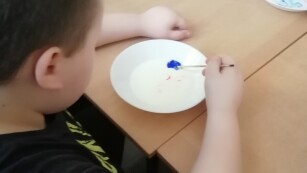 Chłopiec maluje w mleku